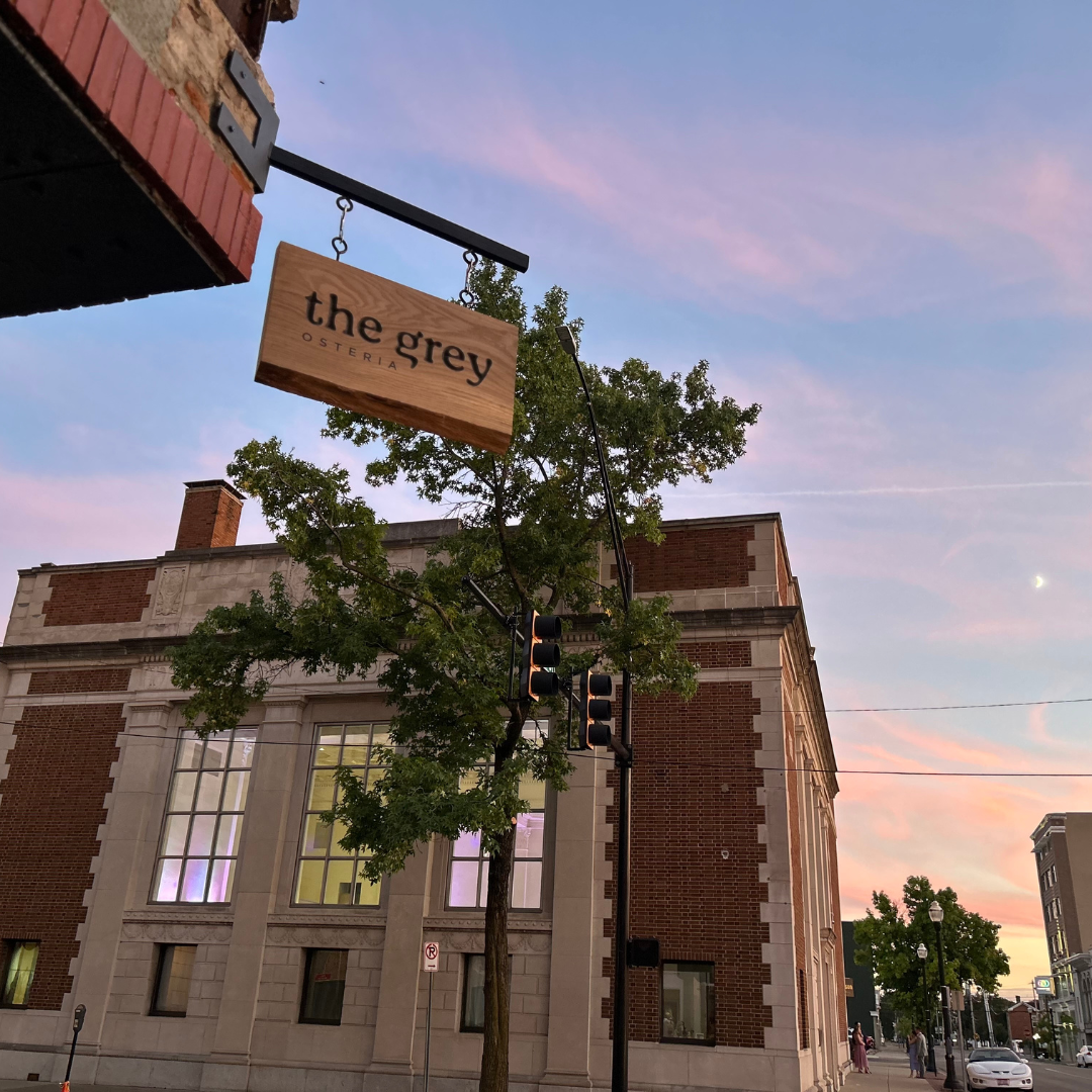 The Grey entry sign with a brick building and sun setting in the background